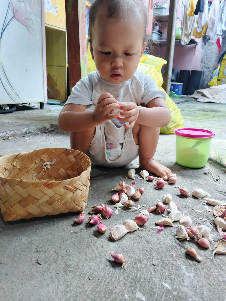 Anak bereksplorasi dengan bahan dapur dan keranjang di rumah